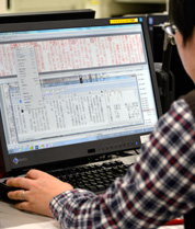 新聞共有システムの組版システムの画面にて紙面制作を行っている整理部員